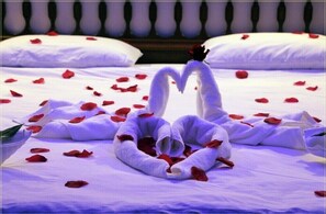 Relax in a cozy retreat with a neatly made bed, complete with a romantic touch of fresh towels and rose petals.