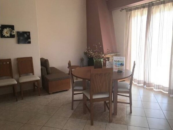 A room with a round table, two wooden chairs, a sofa, and a small decorative plant.