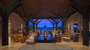 A spacious lounge area with a long table, seating, and a view of the ocean. - Dreams Natura Resort & Spa - All Inclusive (Puerto Morelos)