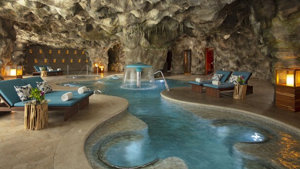 A spa area with a hot tub, lounge chairs, and a waterfall feature. - Dreams Natura Resort & Spa - All Inclusive (Puerto Morelos)