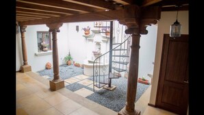 A courtyard with a spiral staircase, wooden columns, and potted plants. - Casa Girasol (Antigua Guatemala)