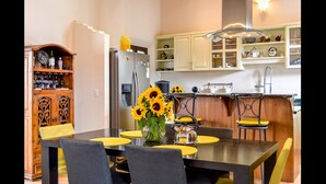 A modern kitchen with a dining table, chairs, and a vase of sunflowers. - Casa Girasol (Antigua Guatemala)