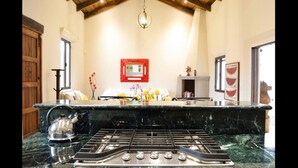 A kitchen with a marble countertop, a gas stove, and a hanging light fixture. - Casa Girasol (Antigua Guatemala)