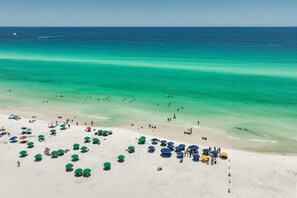 A beach with numerous umbrellas and people enjoying the water.