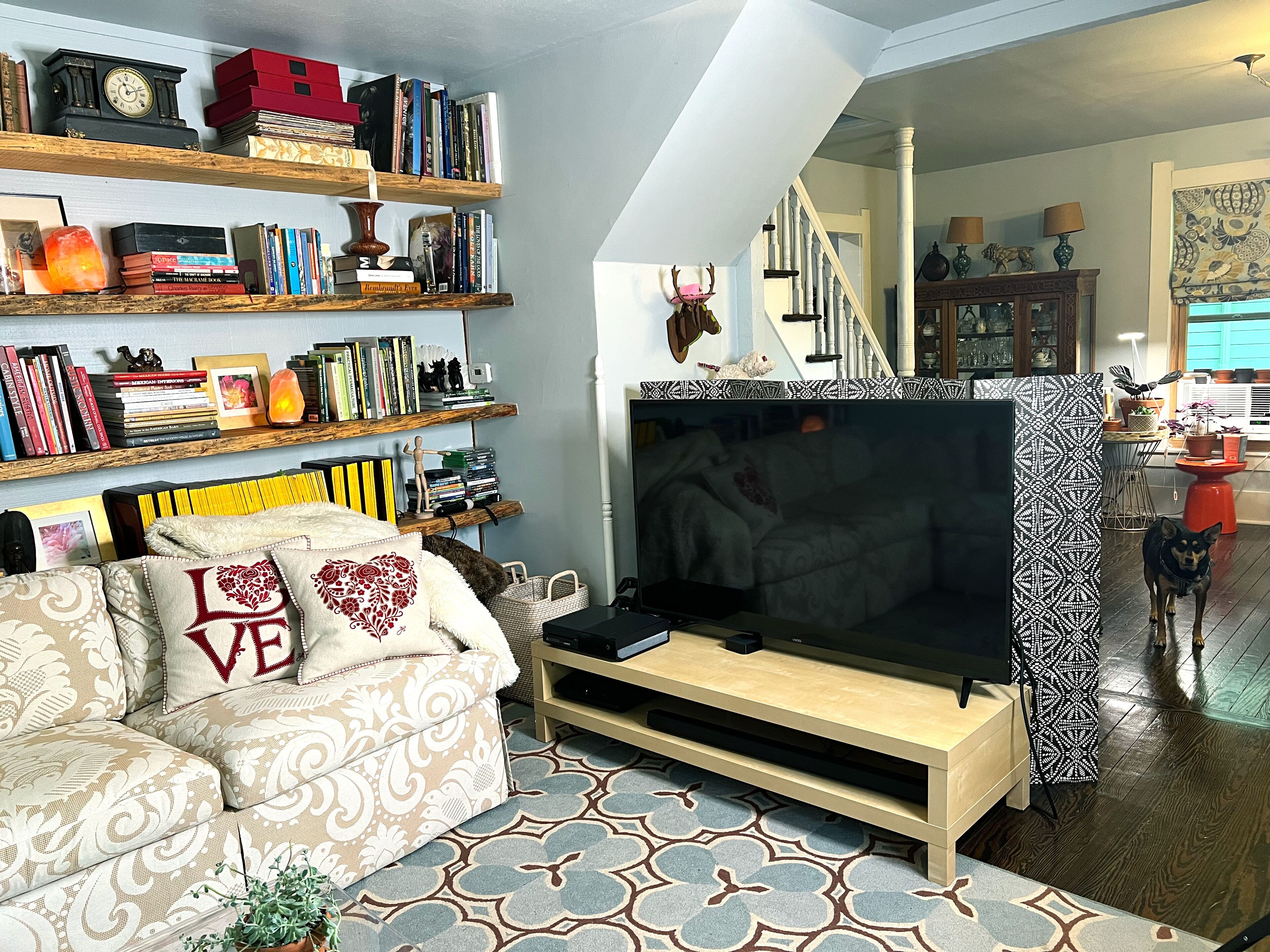 Un salon avec un canapé, un téléviseur, une bibliothèque et un escalier.