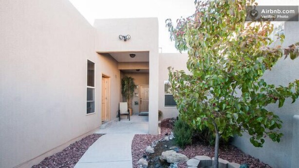 A narrow pathway leading to a building with a small garden area with a tree and decorative rocks. - Separate Private Detached 1 Room Casita with your own entrance (Albuquerque)