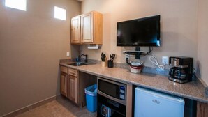 A compact kitchen with wooden cabinets, a built-in TV, a coffee maker, and a mini fridge. - Separate Private Detached 1 Room Casita with your own entrance (Albuquerque)
