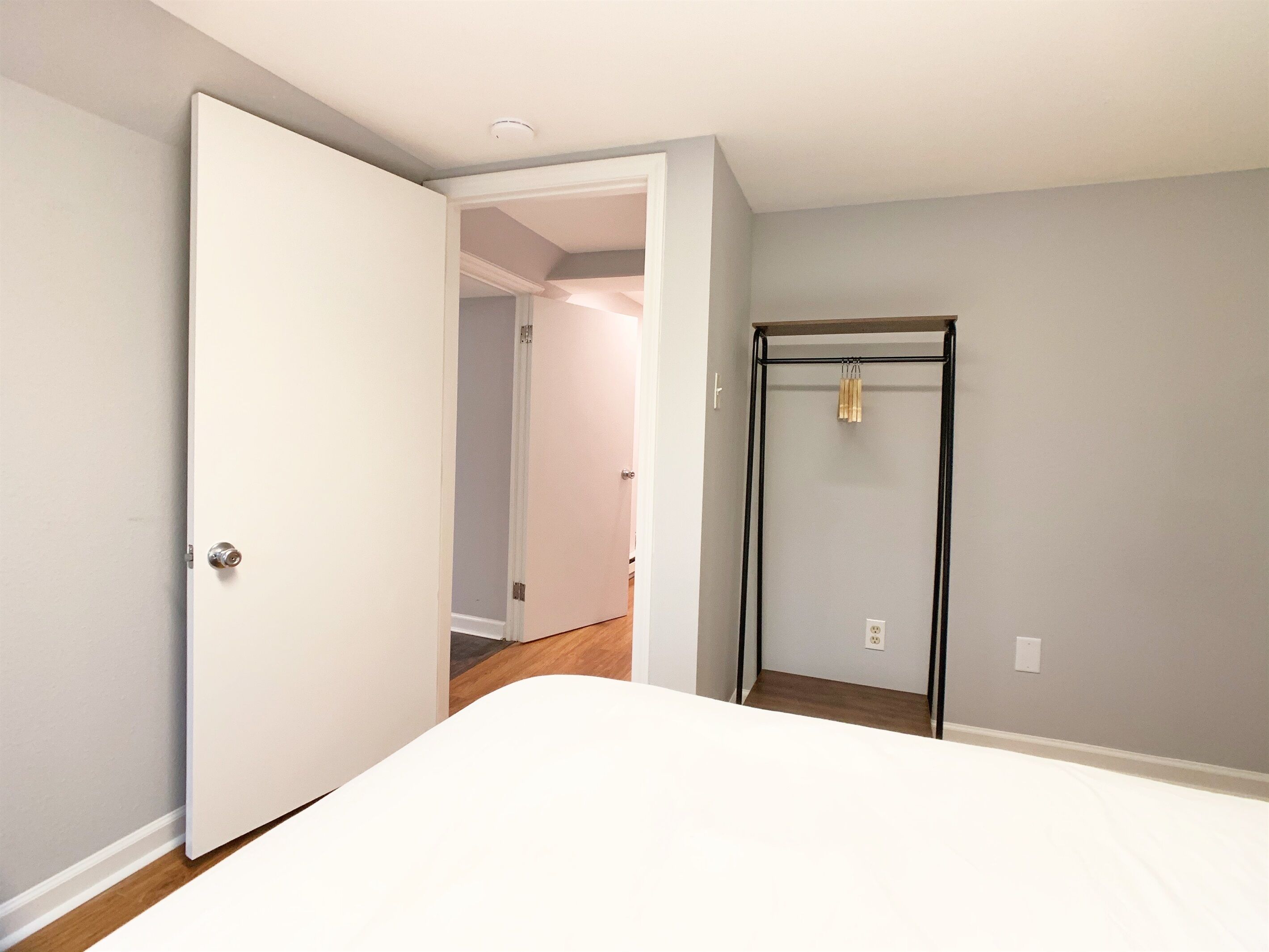 A bedroom with a bed, a wardrobe, and a door leading to another room.