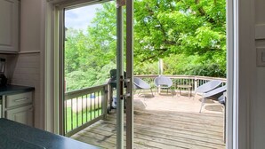 A kitchen with a sliding glass door leading to an outdoor deck with chairs and a grill.