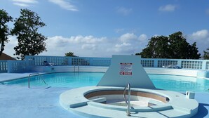 En pool med et skilt, der viser 'No Diving', et spabad og liggestole.