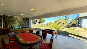 Zona de juegos interior con mesa de billar, sillas y mesa de futbolín.