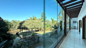 Ein modernes Interieur mit Glaswand, Fliesenboden und Blick auf einen angelegten Garten.