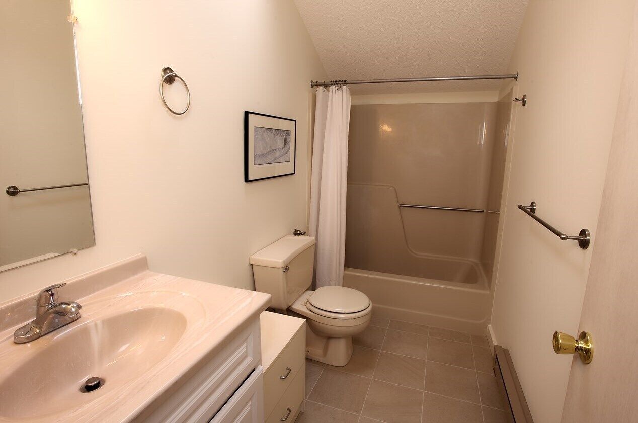 A small, clean bathroom with a sink, toilet, and shower.