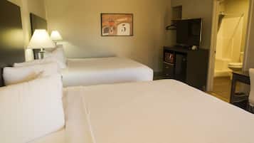A hotel room with two beds, a TV, a desk, and a shower area.