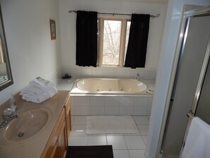 Een badkamer met een bad, een wastafel en een raam met gordijnen.