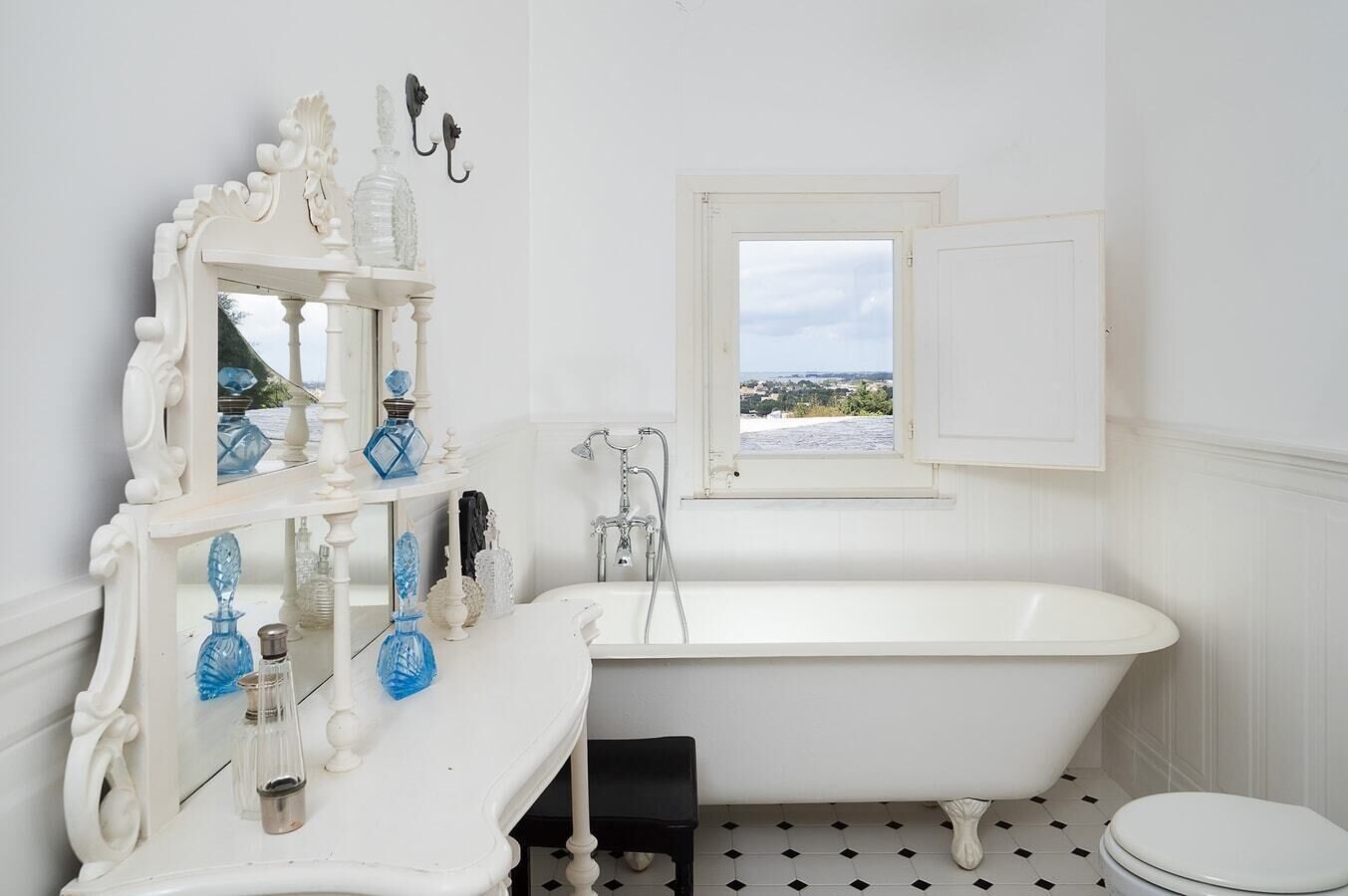Un baño con una bañera blanca, un tocador con espejo y una ventana con vistas.