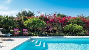 A clear blue swimming pool with a white deck, surrounded by lush greenery and pink flowers. - Villa Addolorata - Private villa near Marsala (Marsala)