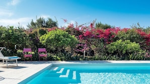 A clear blue swimming pool with a white deck, surrounded by lush greenery and pink flowers. - Villa Addolorata - Private villa near Marsala (Marsala)
