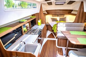 Cozy motorhome interior with a kitchenette, dining area, and sleeping space.