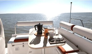 Enjoy a meal on the boat with a view of the open water and distant shoreline.