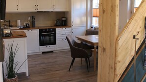 Moderni keittiö, jossa on valkoiset kaapit, puinen työtaso sekä ruokailutila, jossa on pöytä ja tuolit.
