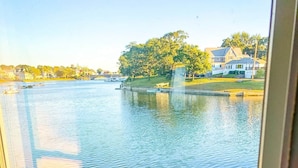 Une vue à travers une fenêtre sur un lac, avec des maisons en arrière-plan.