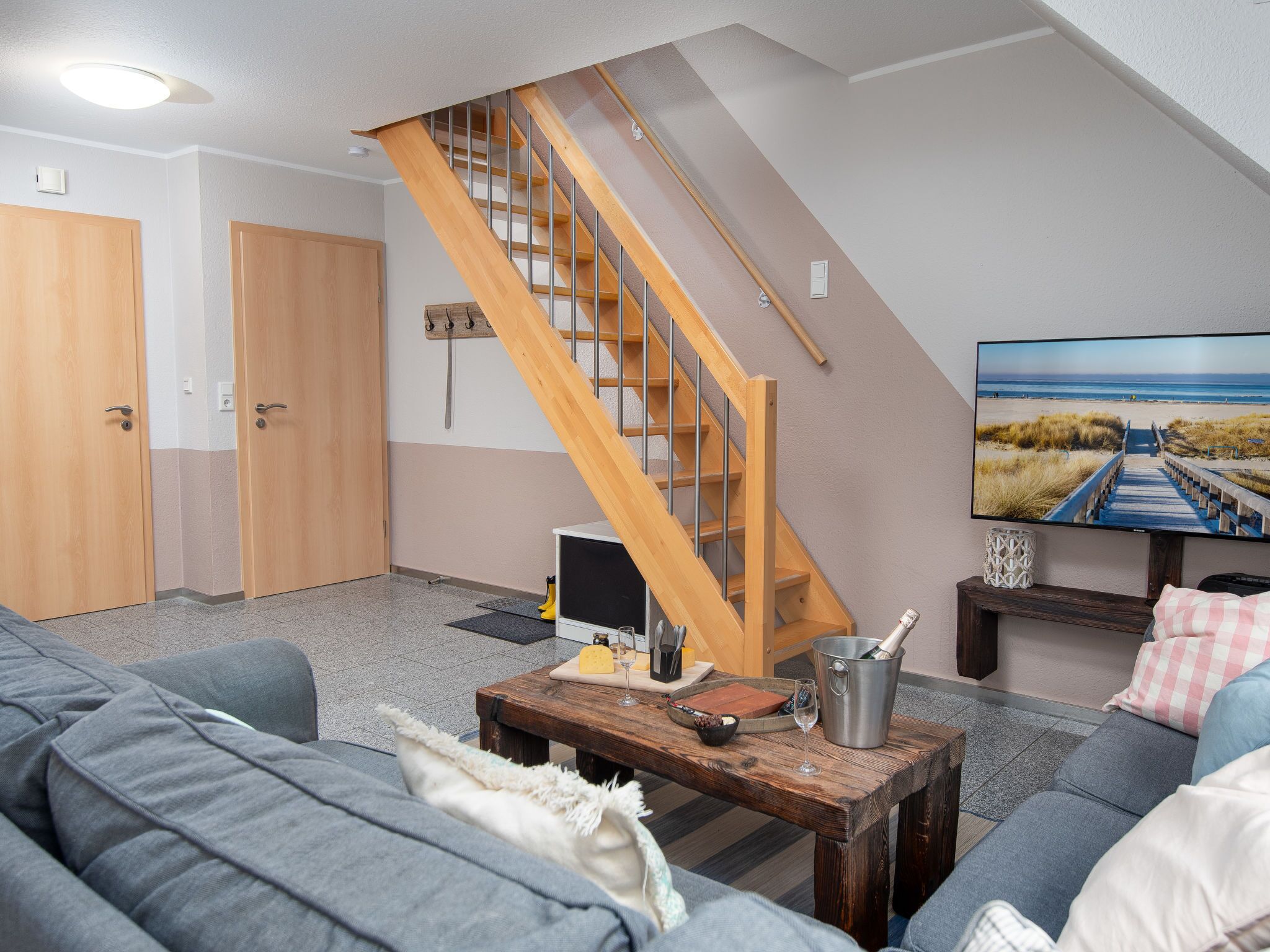 Ein Wohnzimmer mit Holztreppe, einem Fernseher und einem Sofa.