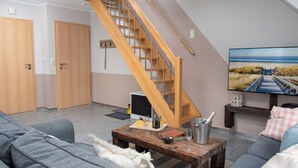 Ein Wohnzimmer mit Holztreppe, einem Fernseher und einem Sofa.