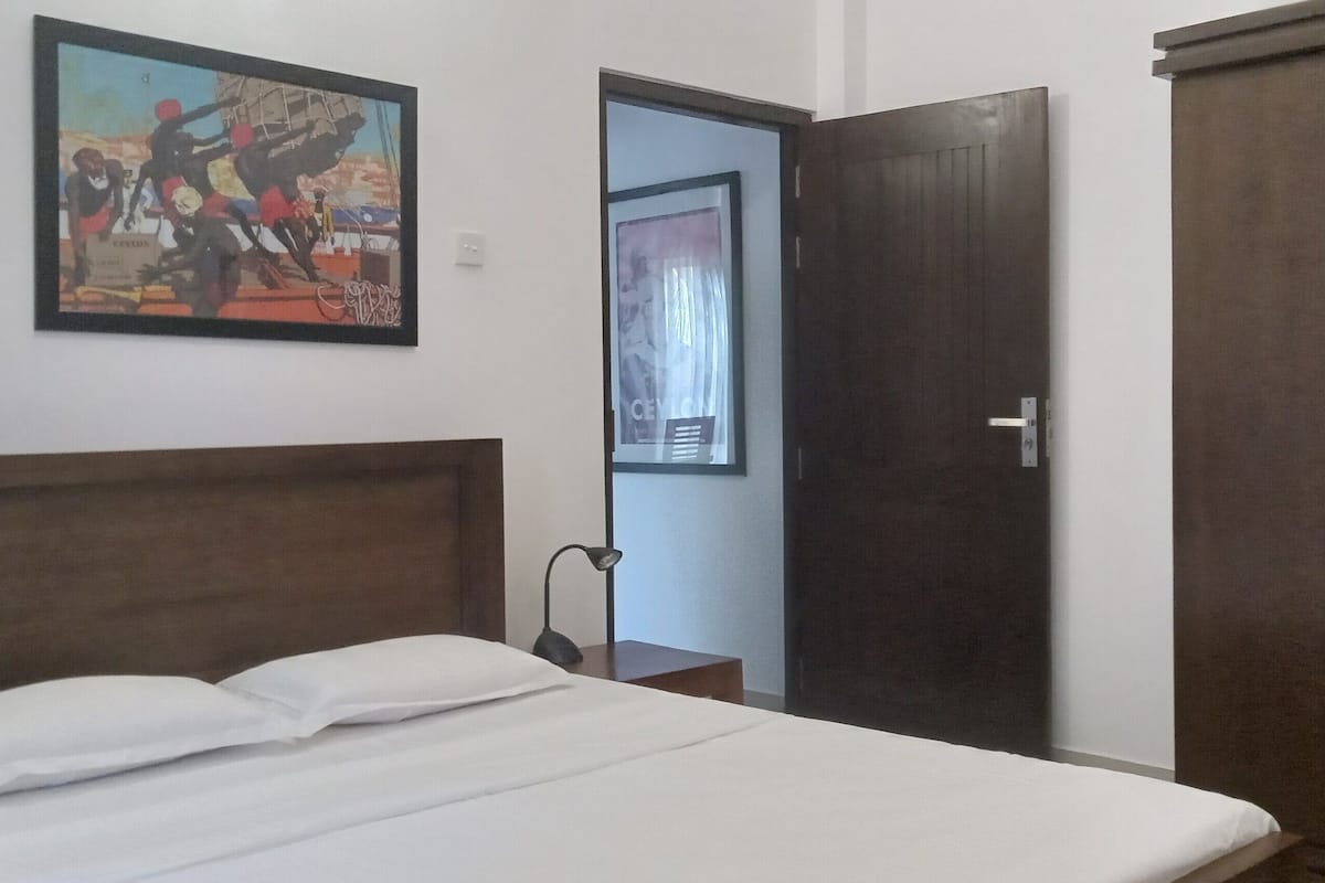 A bedroom with a bed, a wardrobe, and a door leading to another room.