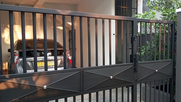 Ein verschlossenes Tor, innerhalb ist ein Auto geparkt.