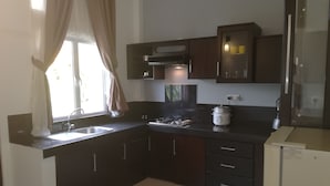 Eine moderne Küche mit dunklen Schränken, einem Gasherd, einer Spüle und einem kompakten Kühlschrank.
