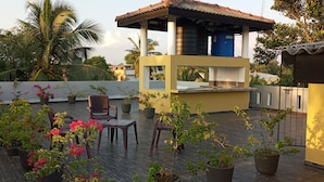 Eine Dachterrasse mit Topfpflanzen, Gartenmöbeln und einem Wassertank.