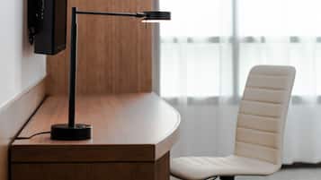 Un escritorio moderno con una lámpara negra, una silla blanca y un televisor montado.