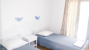 A room with two single beds, a small bedside table, and a wall-mounted light fixture. - Zakynthos-Summer Sea View (Zakynthos)
