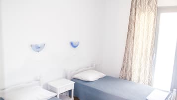 A room with two single beds, a small bedside table, and a wall-mounted light fixture.