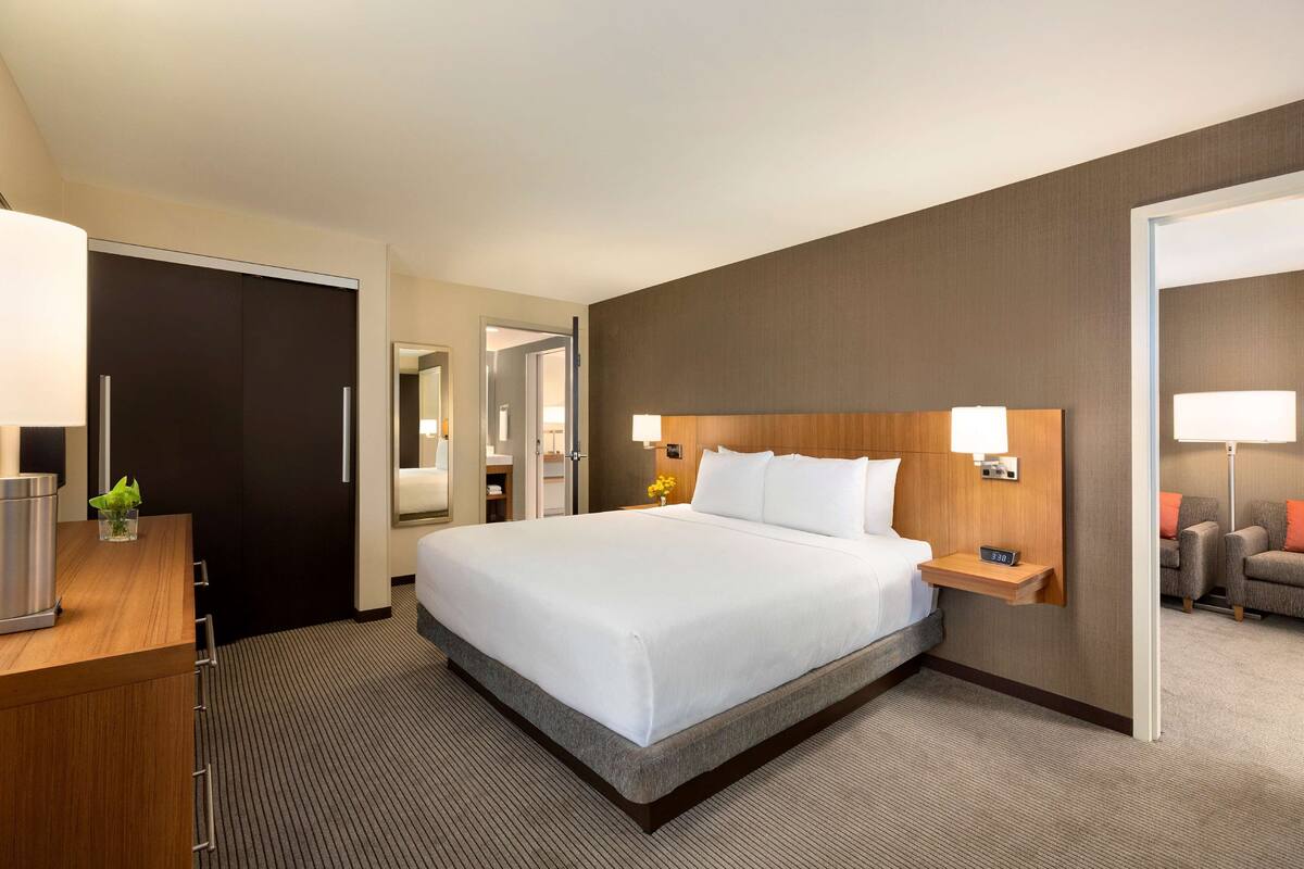 A hotel room with a large bed, bedside tables, a desk, and a chair.