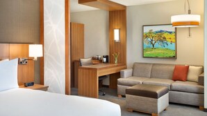 A hotel room with a bed, a desk, a sofa, and a painting on the wall. - Hyatt Place Vacaville (Vacaville)