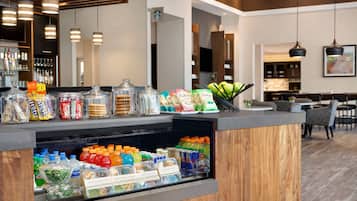A hotel reception area with a counter displaying snacks, bottled water, and juice.
