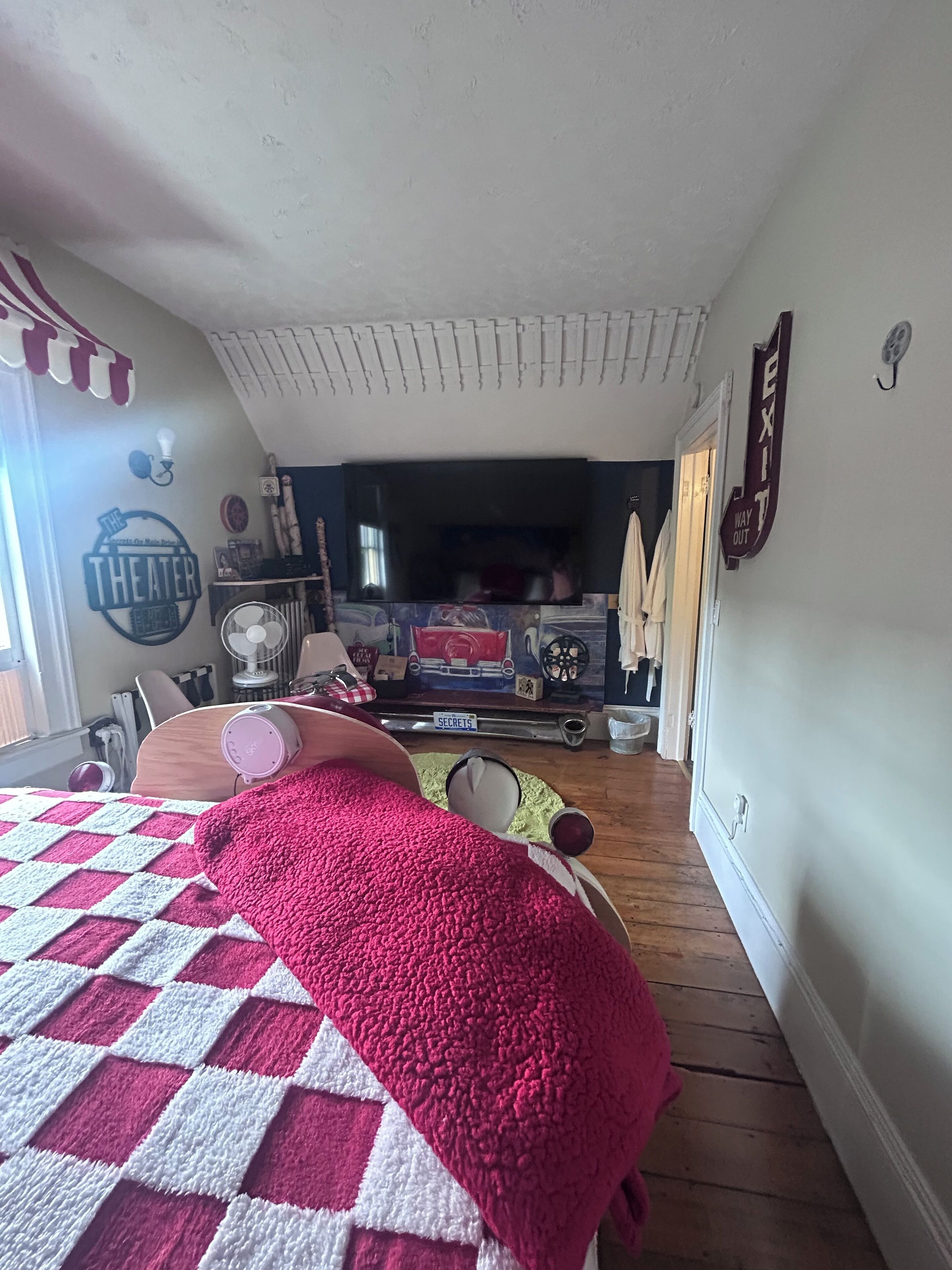 A cozy room with a large bed, a television, and a sign that says "Theater".