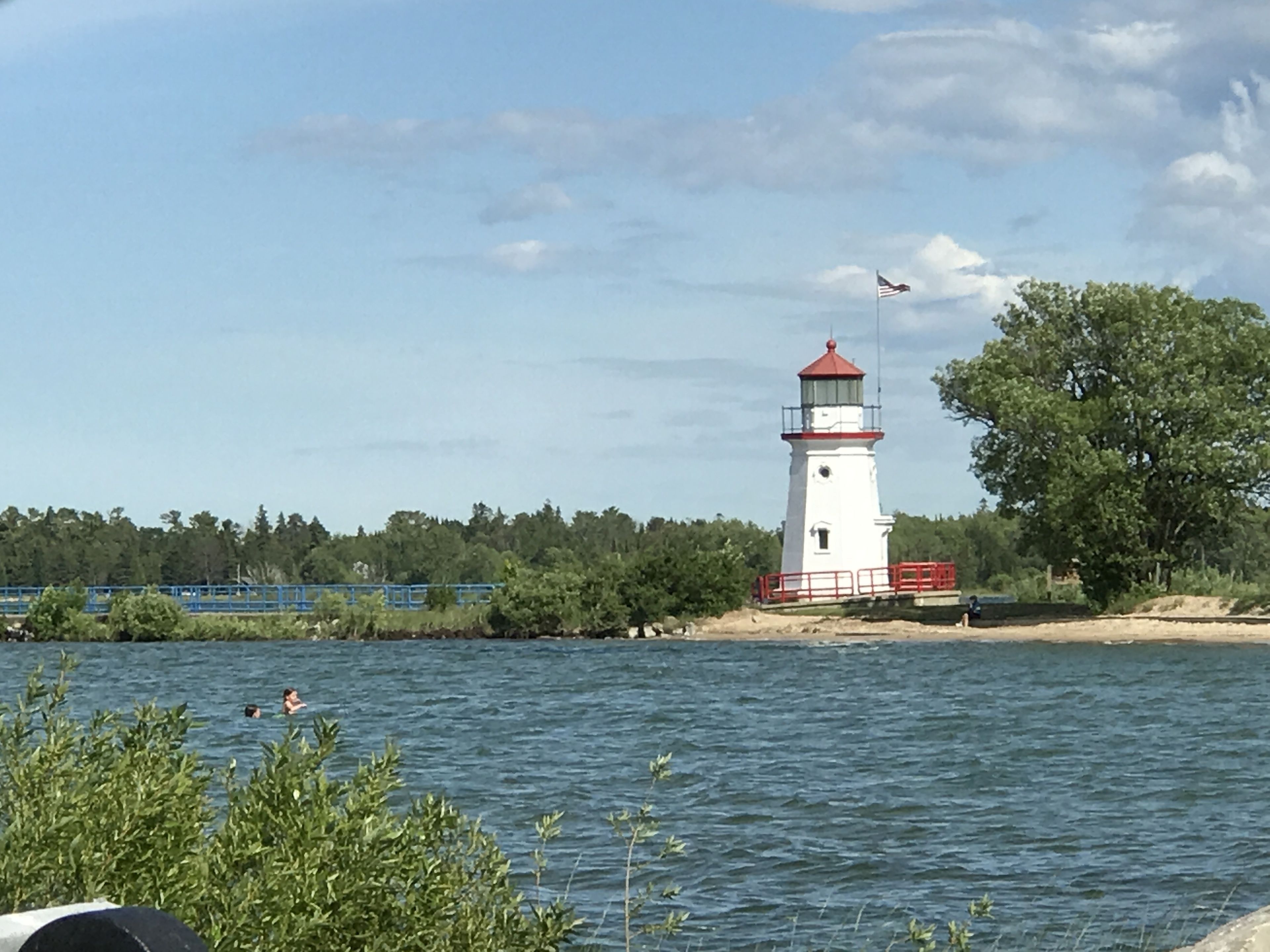 A lighthouse by a body of water with a clear sky.