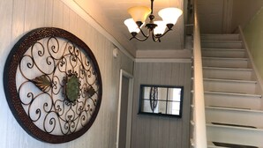 Un escalier avec des marches blanches et une rampe noire, menant à un palier agrémenté d’un élément décoratif mural et d’une fenêtre.