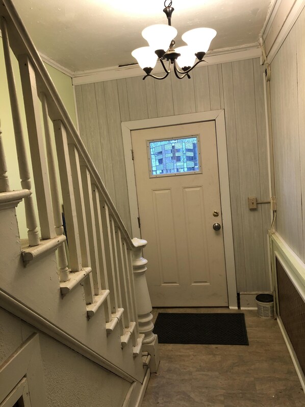 A staircase with white balusters leading to a door with a frosted glass window. - Cozy French Pied a terre - King bed, washer/dryer (Schenectady)