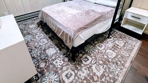 Habitación con literas, una alfombra estampada, una ventana y una mesita de noche.
