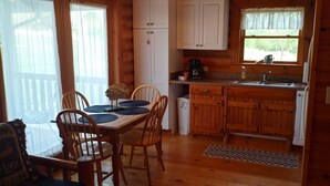 Een houten chalet met een eethoek en keuken.