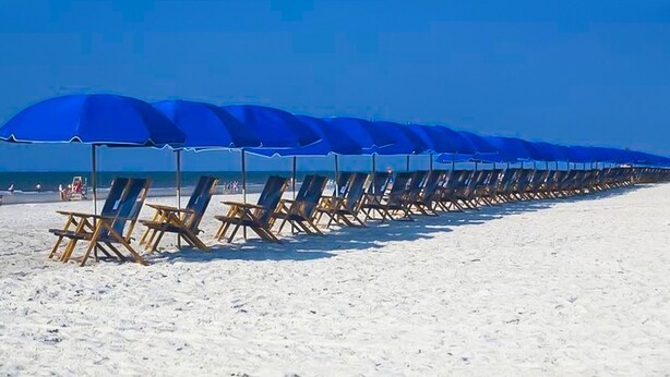A beach with rows of blue umbrellas and wooden lounge chairs. - NEW RESORT-STYLE POOL, CUTE HOUSE, 88 STEPS TO SAND! (Hilton Head Island)