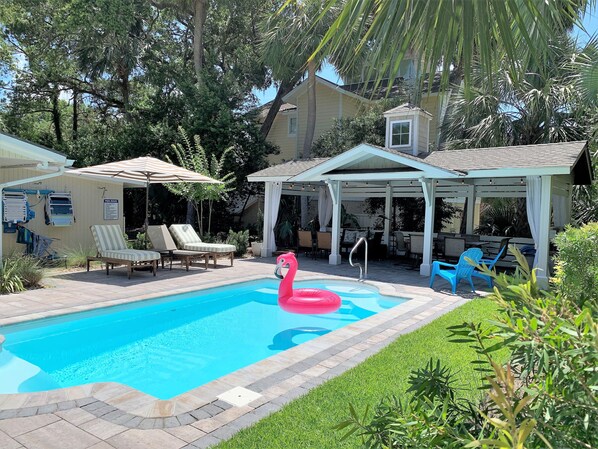 A swimming pool with lounge chairs and a flamingo float.