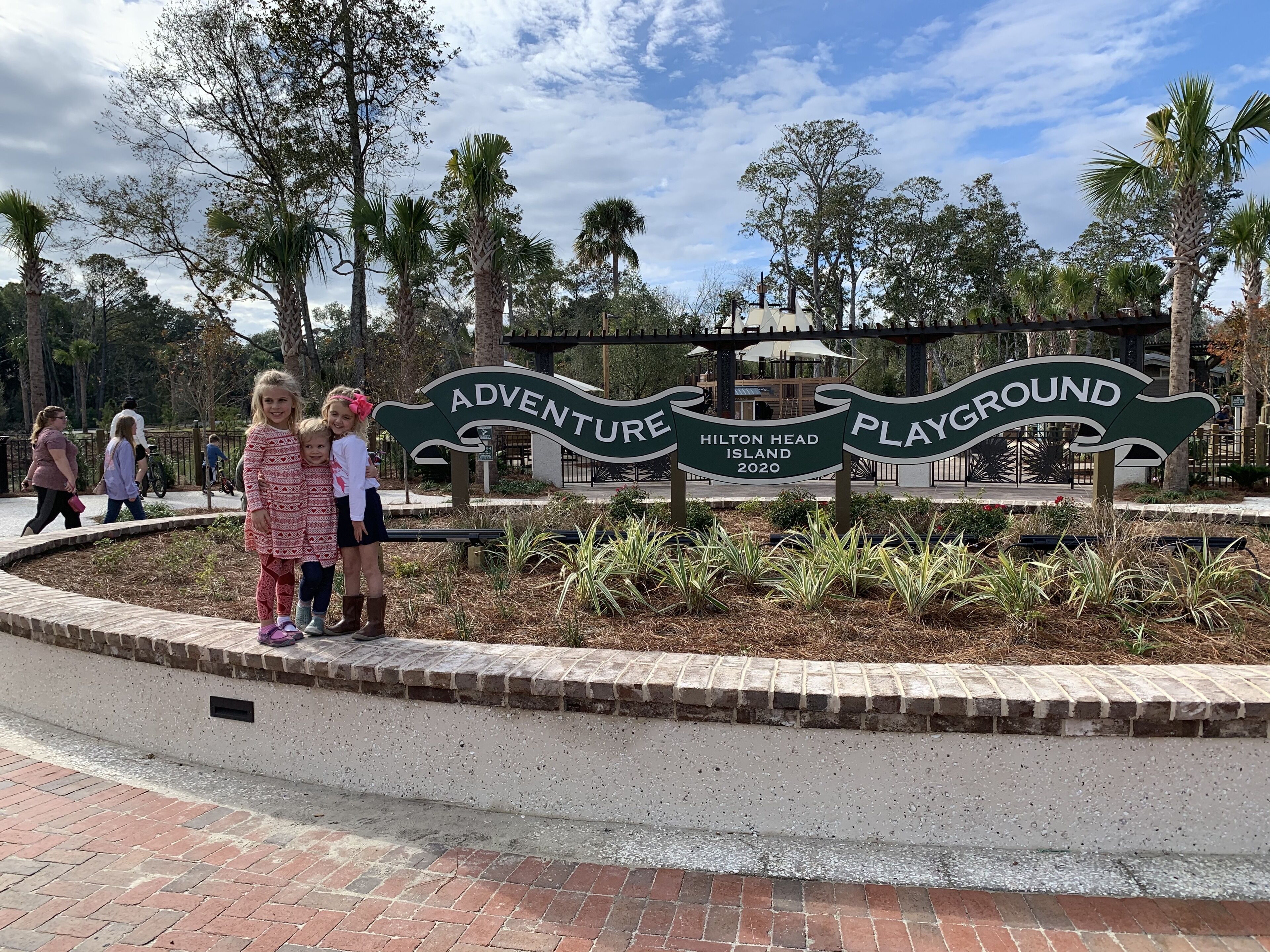 Schild für den Adventure Playground auf Hilton Head Island mit einem Ziegelweg und Palmen im Hintergrund.