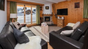 Een gezellige woonkamer met leren banken, een open haard en een televisie.