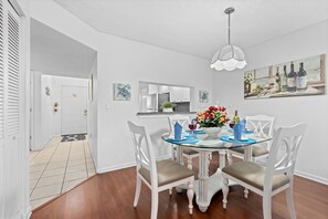 Un coin repas avec une table en verre, des chaises blanches et un lustre.