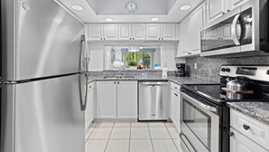 A modern kitchen with stainless steel appliances, white cabinetry, and a tiled floor. - *Casa Mia* Fabulous 2BR Condo w/2Pools, Mins to IMG/Beach/Anna Maria Isl (Bradenton)